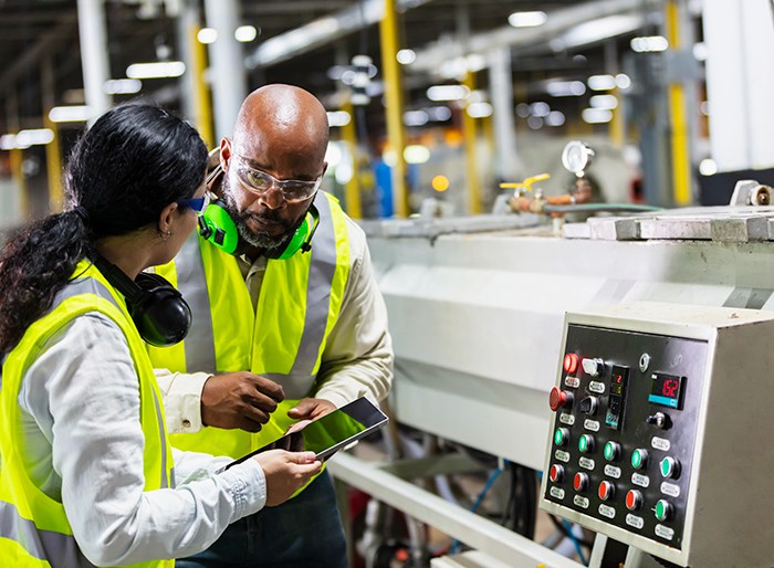 Multiracial workers in factory at machine control panel