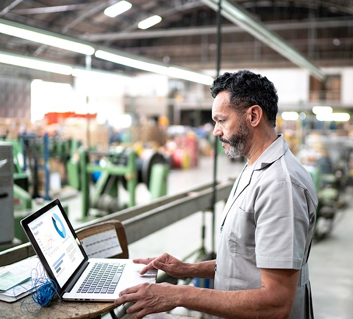 Manufacturing General Manager uses Genius Shop Floor software on a laptop in a manufacturing plant