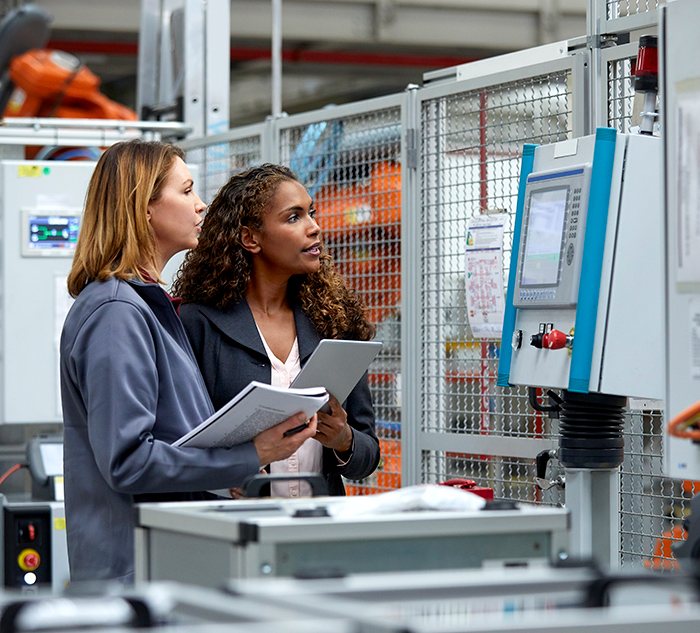 Two female Shop Floor experts inspect machine operations