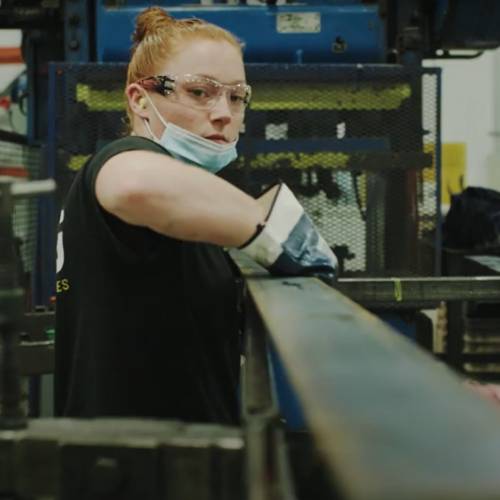 female worker in mask working on manufacturing line