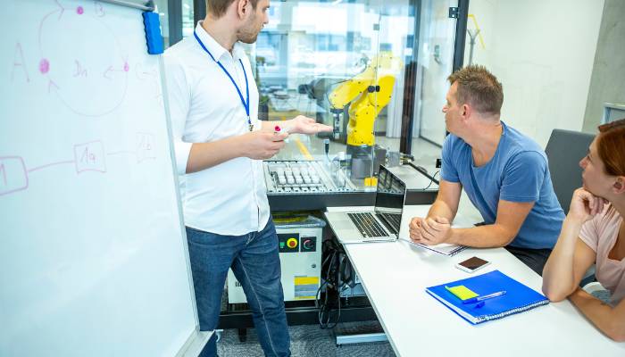 Employees talking about robotics in front of white board